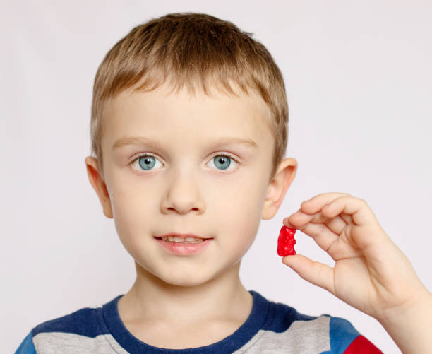 Boy, holds in hand, wants to eat gelatinous sweets, gummy bear, concept of children's delicacy, healthy and unhealthy food Boy, holds in hand, wants to eat gelatinous sweets, gummy bear, concept of children's delicacy, healthy and unhealthy food. food elementary student healthy eating schoolboy stock pictures, royalty-free photos & images