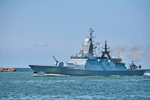 Battleship war ship corvette with helicopter on deck performing military exercises in Baltic Sea. Warship boat carrying helicopter sailing in beautiful blue sea. Military warship, Russian Navy