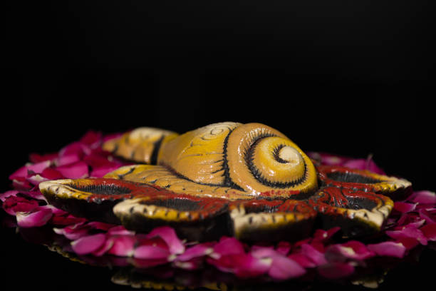Eco-Friendly Clay Shankh Diya Deep Dia arranged on rose petals as rangoli background with copy space