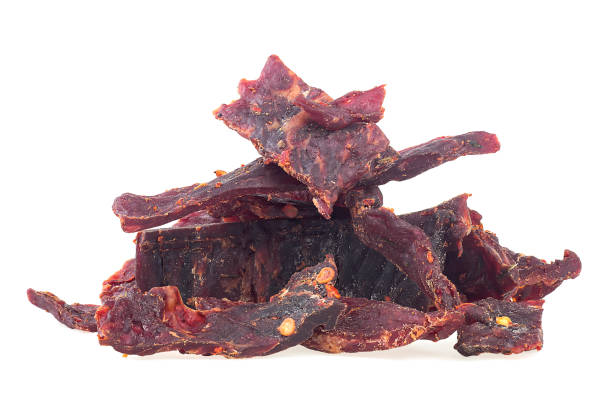 istock Portion of spiced beef jerky isolated on a white white background. Dried peppered beef jerky. 1349461404