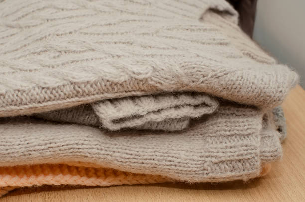 istock Knitted warm sweaters stacked in a pile, neutral background. 1349461874