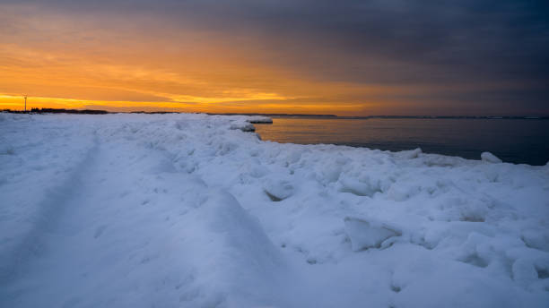 istock Bright orange winter sunset over the sea, beach covered with snow 1349462655