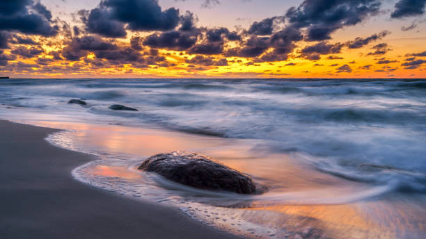 istock Rocky seashore, bright orange sunset on the background 1349462667