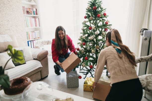 istock Two women placing presents under a Christmas tree 1349465322