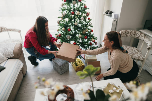 istock Two women placing presents under a Christmas tree 1349465323