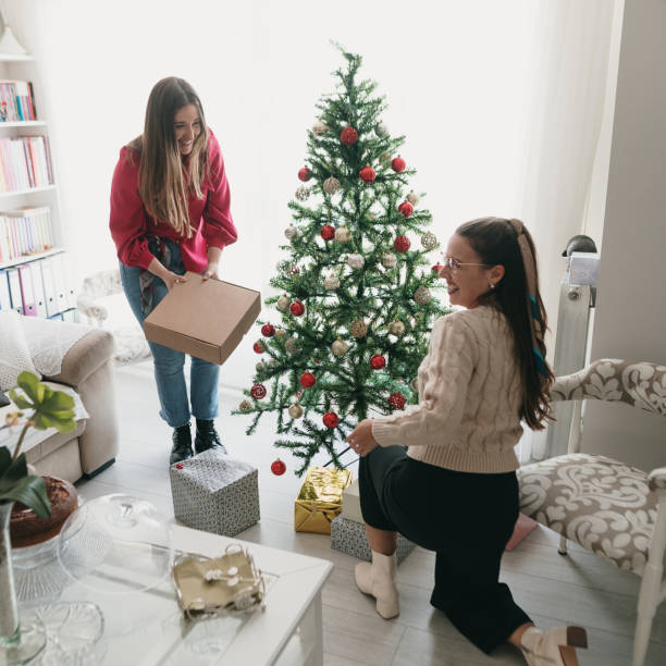 istock Two women placing presents under a Christmas tree 1349465364