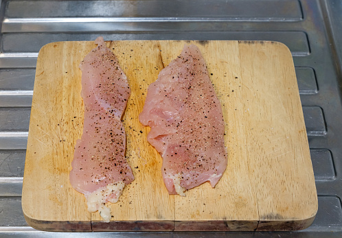 Two raw chicken drumsticks and legs in cooking pan with oil