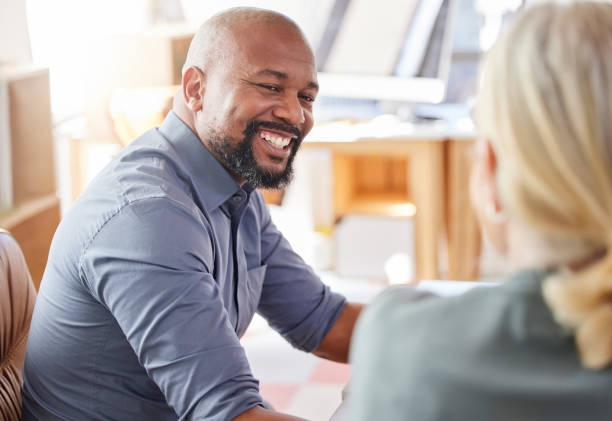 tiro de um homem de negócios sorrindo enquanto falava com um colega - defocused business office casual - fotografias e filmes do acervo