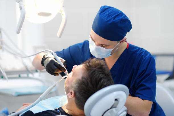 Dentist and patient at medical center. Doctor treats a mature man teeth with dental drill. Orthodontist and prosthetics appointment. stock photo
