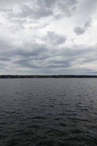 Dark stromy cloudscape in Baltic sea. Many dark clouds with sunlight coming through. Water surface. Horizon line. Tallinn, Estonia, August 2021.