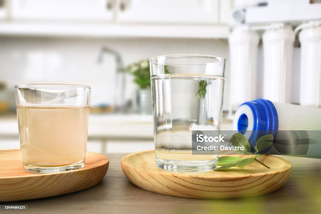 Comparison of dirty and filtered water by osmosis front view Comparison of dirty water and filtered by osmosis in glasses on a kitchen bench with filter and equipment in the background. Front view. Horizontal composition. Water Stock Photo