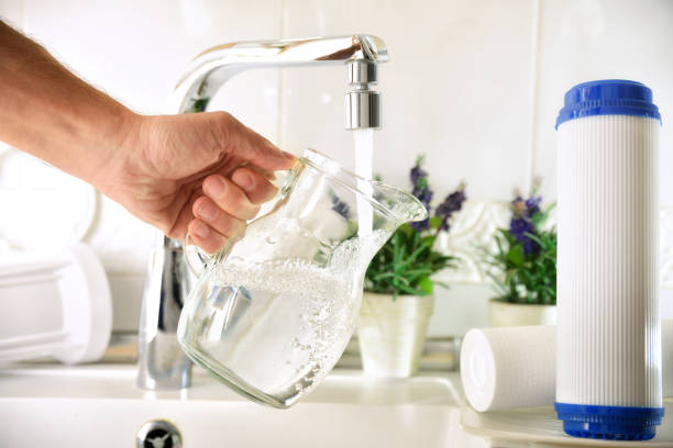 handfüllkanne aus einem wasserhahn mit gefilterten osmosewasser - impurities stock-fotos und bilder