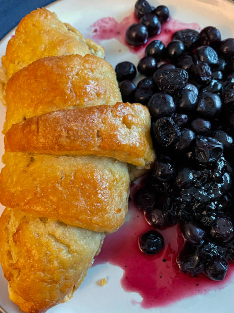 Full frame image of blue rimmed plate with breakfast of freshly baked croissant and blueberry jam, elevated view