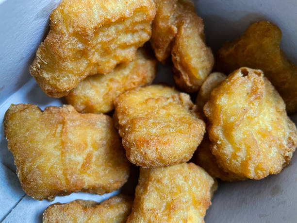 istock Full frame image of grease stained, disposable, cardboard box containing freshly fried chicken nuggets, fast food takeaway, elevated view 1349485629