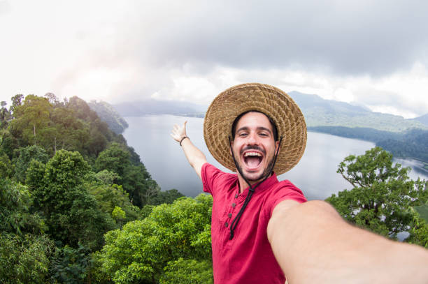 Happy handsome man posing and taking a selfie on a nature landscape