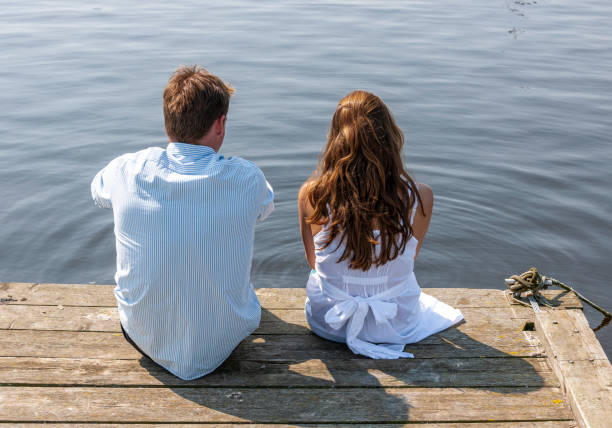 istock Loving couple sitting on pier at waterfront 1349485784