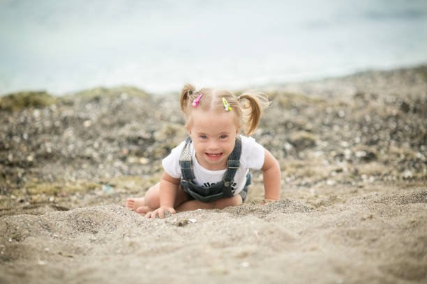 istock Girl with Down syndrome funny crawling on the beach 1349489331