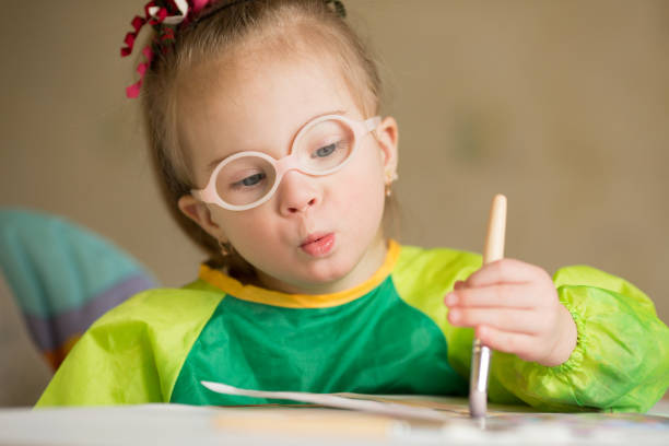 istock Girl with Down syndrome covered in paint when drawing 1349489507