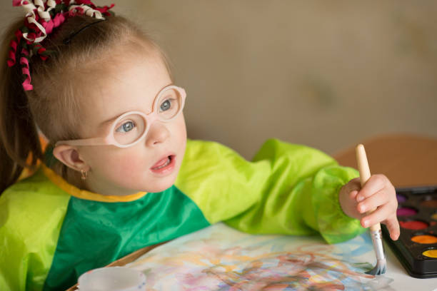 istock Girl with Down syndrome covered in paint when drawing 1349489547