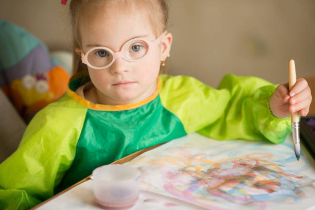 istock Girl with Down syndrome covered in paint when drawing 1349489813
