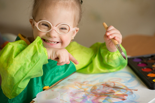 Niña con síndrome de Down cubierta de pintura al dibujar photo