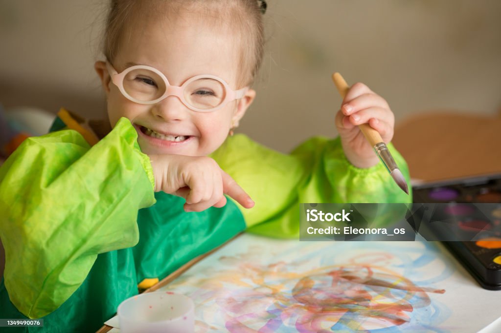 Girl with Down syndrome covered in paint when drawing Down Syndrome Stock Photo