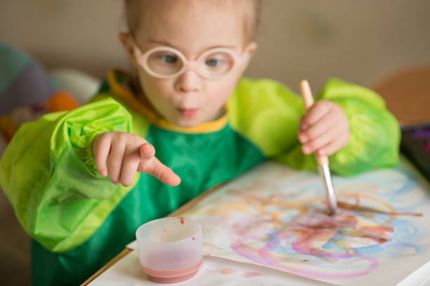 istock Girl with Down syndrome covered in paint when drawing 1349490084