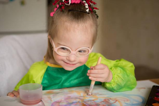 istock Girl with Down syndrome covered in paint when drawing 1349490089