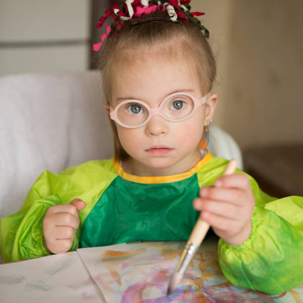 istock Girl with Down syndrome covered in paint when drawing 1349490103
