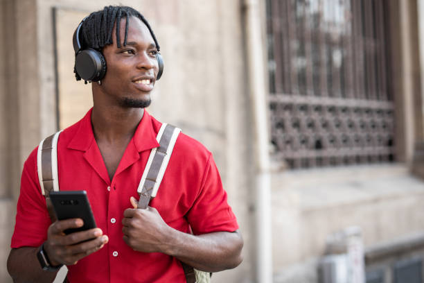 Portrait of a handsome afro man using modern contemporary technologies, phone and wifi wireless headphones