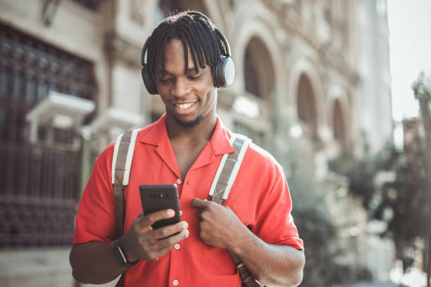 istock Portrait of a handsome afro man using modern contemporary technologies, phone and wifi wireless headphones 1349490109