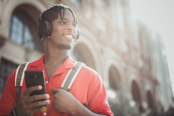 istock Portrait of a handsome afro man using modern contemporary technologies, phone and wifi wireless headphones 1349490110