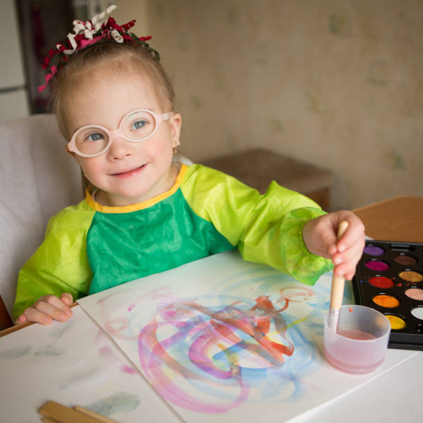 istock Girl with Down syndrome covered in paint when drawing 1349490114