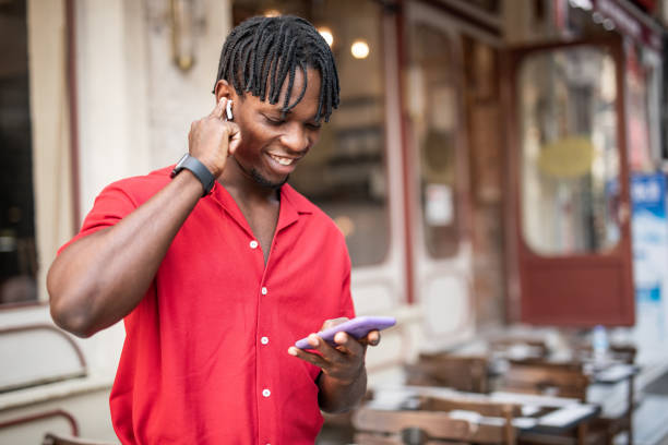 istock Portrait of a handsome afro man using modern contemporary technologies, phone and wifi wireless headphones 1349490138