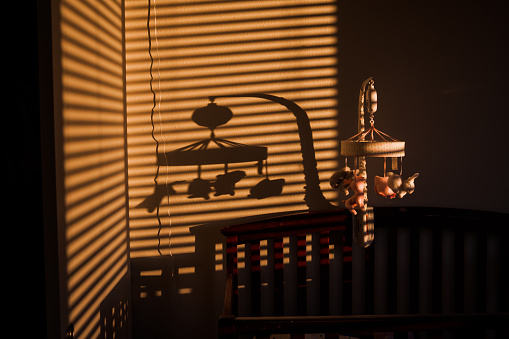 Baby Mobile and shadow above a baby crib in the bedroom