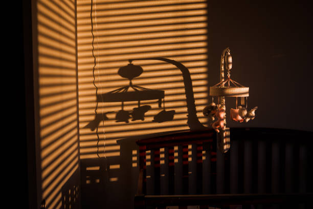 Baby Bedroom Baby Mobile and shadow above a baby crib in the bedroom hanging mobile stock pictures, royalty-free photos & images