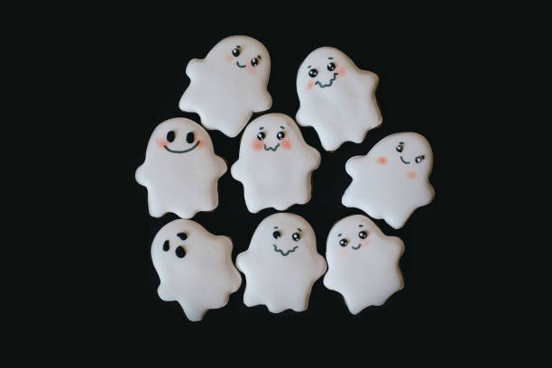 istock Funny scary Halloween ghost cookies with white icing on black tray. 1349497798