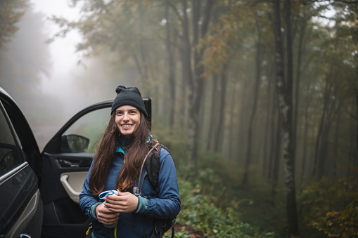 Woman getting out of car for a hike in nature during autumn