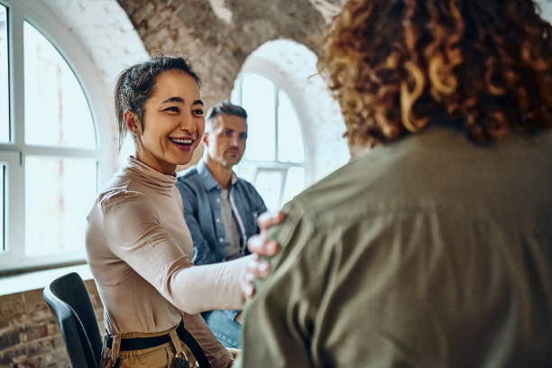 hombres y mujeres sentados en círculo durante la terapia de grupo, apoyándose mutuamente. - mental health professional psychiatrist therapy teenager fotografías e imágenes de stock