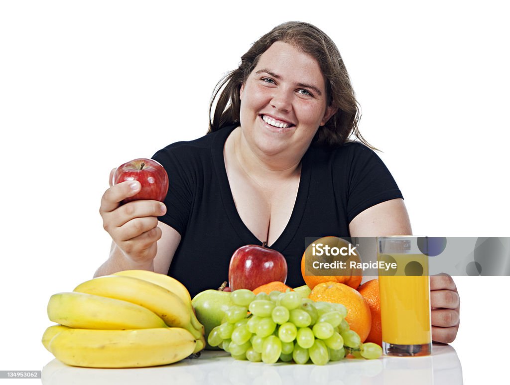 Plump young woman looks up smiling from choice of fruit An overweight young woman looks up smiling as she makes her choice from a selection of healthy fruit. Good for her!  Shot with Canon EOS 1Ds Mark III.  Abundance Stock Photo