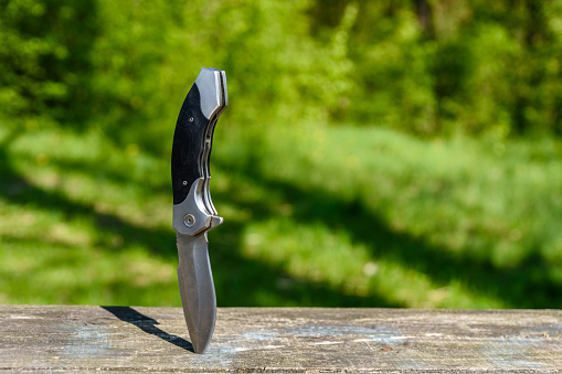 Folding knife stuck in old wooden board