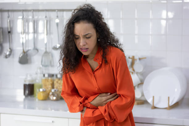 stomach disease, young woman with stomach ache, having food poisoning in kitchen stock photo