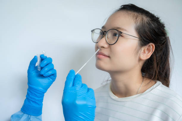 крупным планом руки врача пытаются взять мазок из носа у азиатской женщины для тестирования на диагноз инфекции covid-19. - nasopharynx стоковые фото и изображения