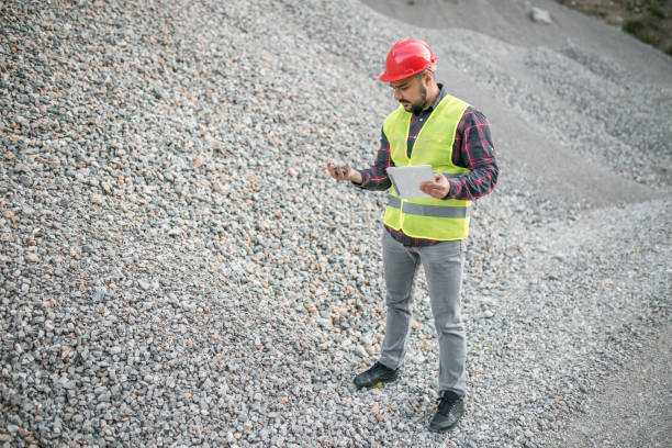 ingegnere barbuto di mezza età con casco che tiene il tablet - construction safety mid adult men road construction foto e immagini stock