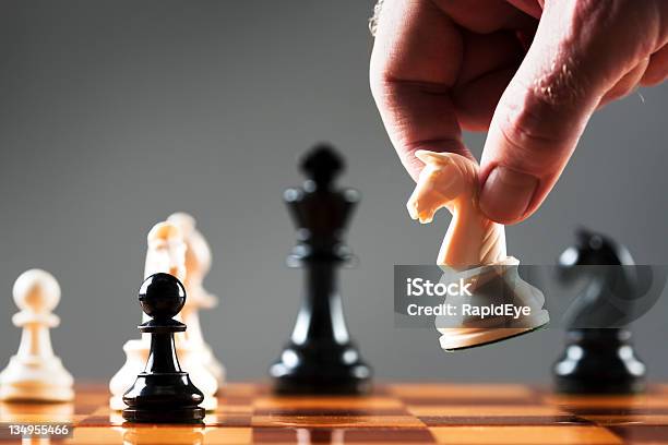 Mans Hand Moves White Knight Into Position On Chessboard Stock Photo - Download Image Now