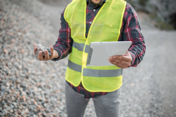 istock Close-up of engineer in quarry examining a stone he has found and holding digital tablet 1349559703