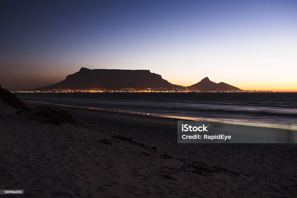 Cape Town's Table Mountain in early evening Looking  across Table Bay to Table Mountain with Cape Town sitting at its foot. It is early evening and a little light remains in the sky, reflected by the city lights beneath.  Shot with Canon EOS 1Ds Mark III  Cape Town Stock Photo