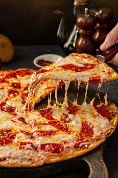 Pepperoni pizza with a slice taken out with cheese pull Pepperoni pizza with a slice taken out with appetizing cheese pull pizza stock pictures, royalty-free photos & images