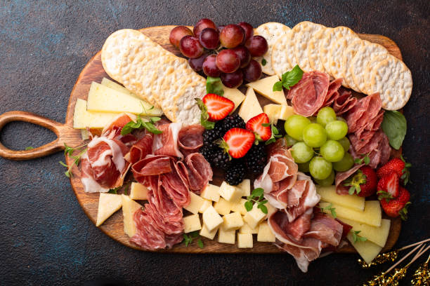 tagliere di salumi con varietà di formaggi e carne - cheese antipasto cracker grape foto e immagini stock