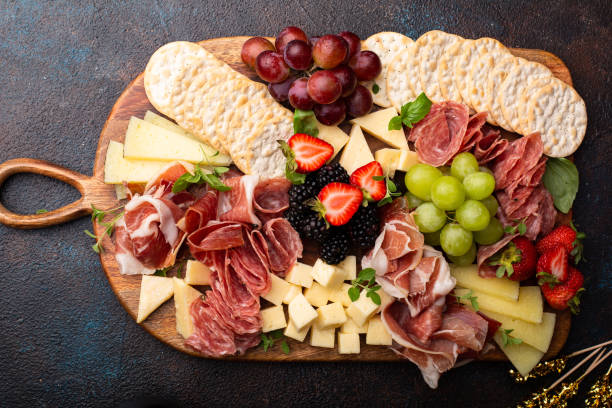 Charcuterie board with variety of cheese and meat Large charcuterie board with variety of cheese and meats charcuterie stock pictures, royalty-free photos & images